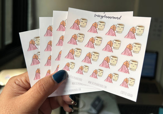 Sheet of printed planner stickers held by a hand with a blurred background